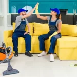 cleaners giving each other high five and continuing to clean the floor in the kitchen.