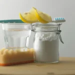 Close-up of baking soda vinegar lemon on table against white background