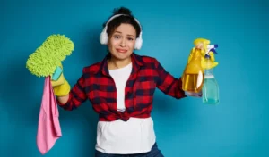 Upset young mixed race woman holding cleaning supplies and products in the hands