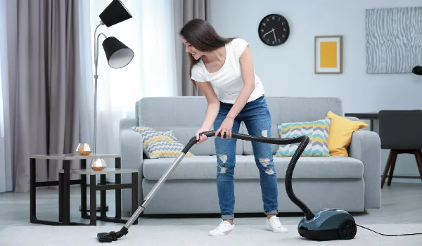 Woman cleaning carpet with vacuum in living room