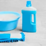 Mopping blue wet microfiber mop with detergent cleaning disinfection kit on a white floor isolated housekeeping concept
