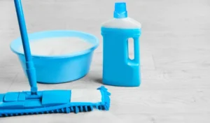 Mopping blue wet microfiber mop with detergent cleaning disinfection kit on a white floor isolated housekeeping concept