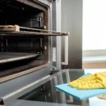 Man with rag and rubber gloves cleaning kitchen oven